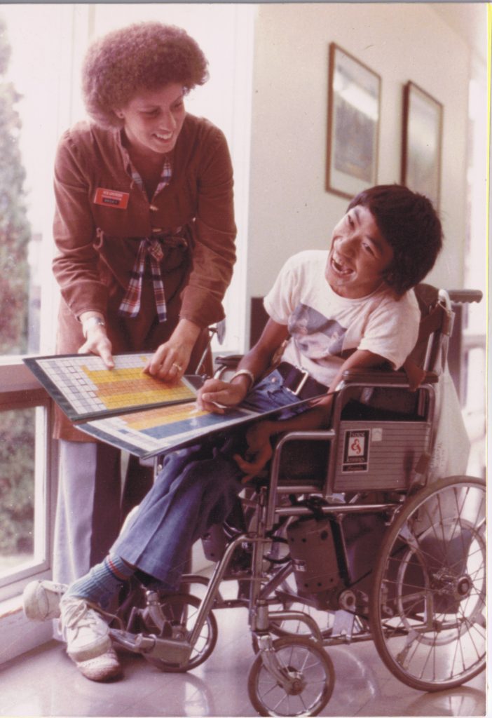 Teenage John sharing a laugh with a Pearson staff member.